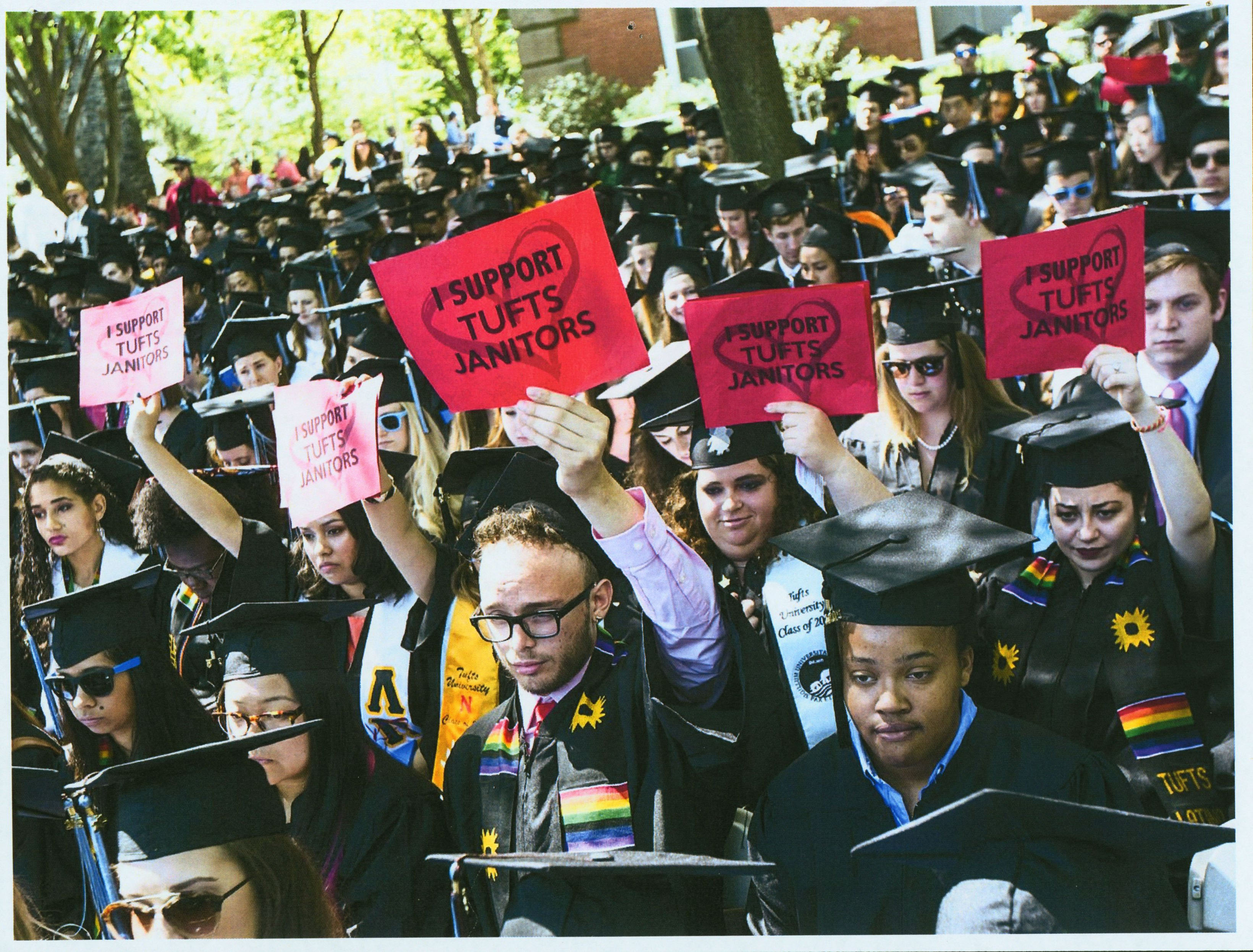 Latinx Center members at graduation holding "We support Tufts janitors" signs. 