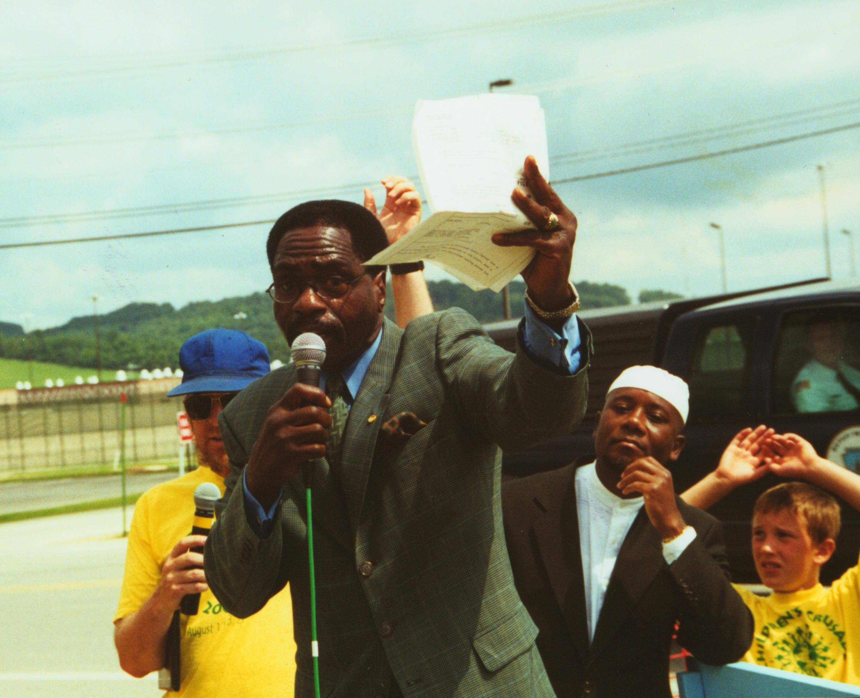 Rubin Carter holding papers and speaking into a microphone