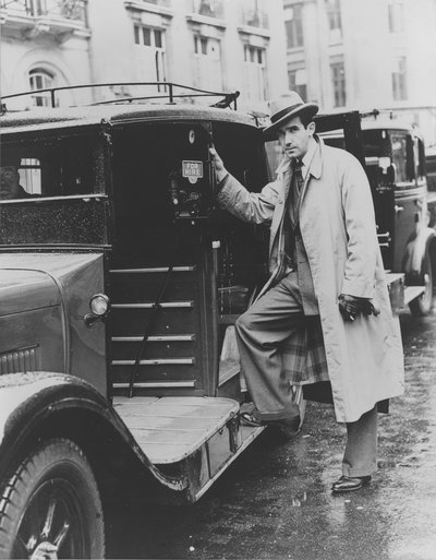 Black and white photograph of Edward R. Murrow standing next to a taxi cab.