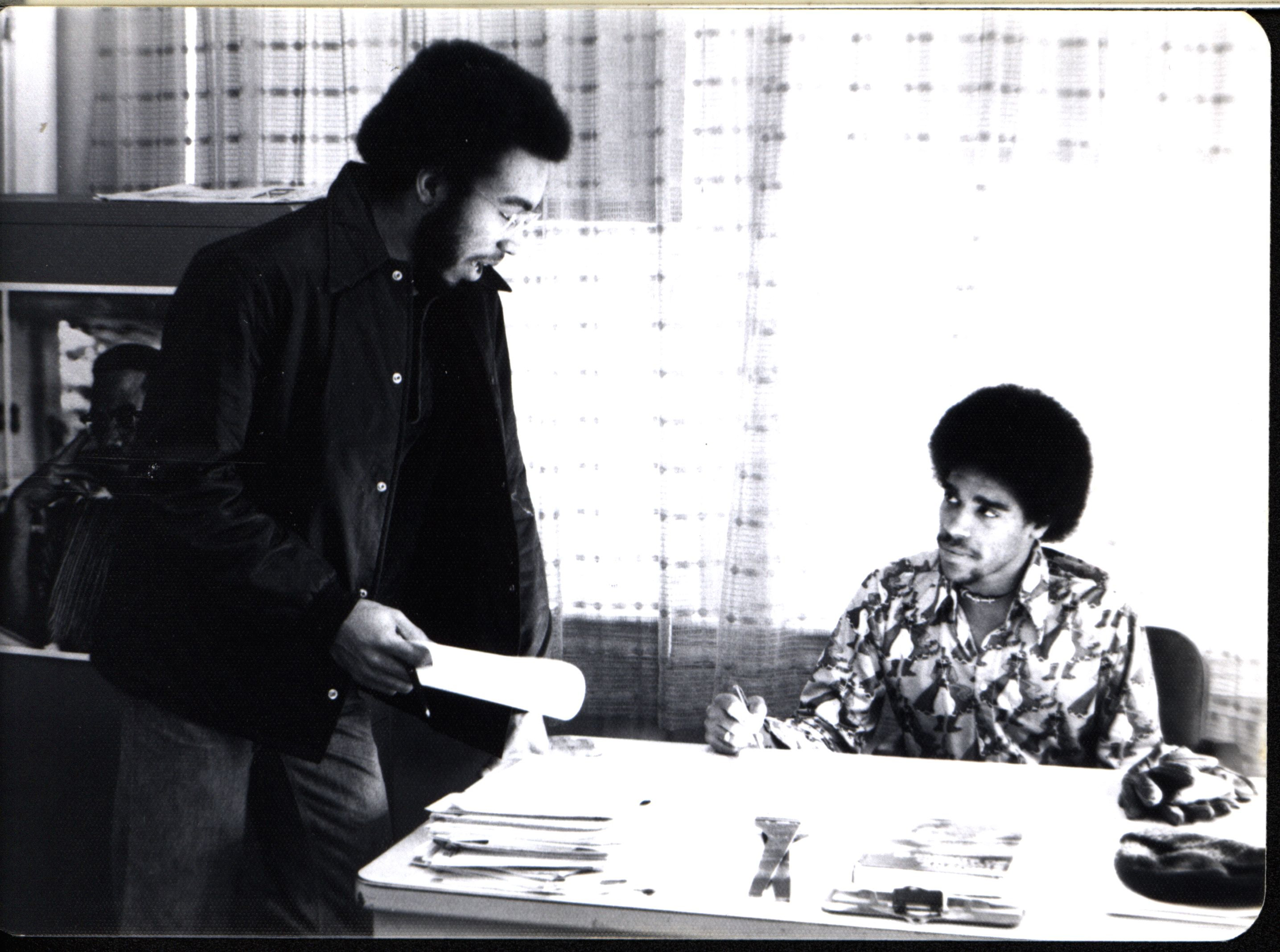 Black and white photo of two young men in an office.