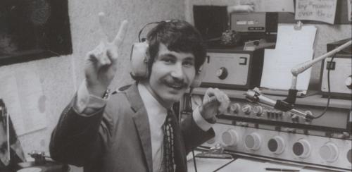 Black and white photo of a WMFO radio host making a peace sign at the camera.